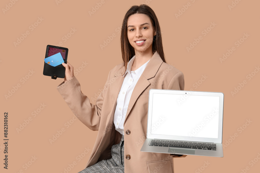 Young woman with credit card holder and laptop on brown background Young woman with credit card holder and laptop on brown background