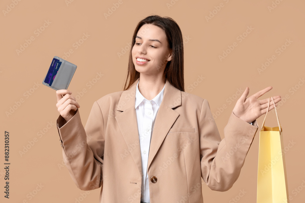 Young woman with credit card holder and shopping bag on brown background Young woman with credit card holder and shopping bag on brown background