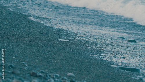 Waves, Foam And Colored Stones. Detail Of The Sea And The Foam Of The Waves On The Pebble Beach.