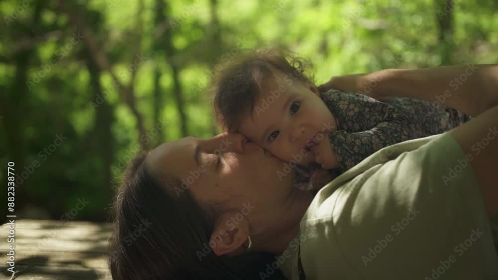 A woman is holding a baby in her arms. The baby is smiling and the woman is kissing the baby's forehead. Scene is warm and loving A woman is holding a baby in her arms. The baby is smiling and the woman is kissing the baby's forehead. Scene is warm and loving