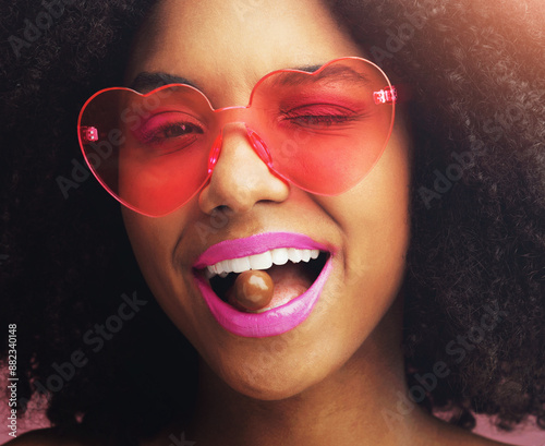 Happy woman, portrait and sunglasses with makeup, chocolate or sweet candy in stylish dessert. Closeup or face of young African, female person or model with wink, cosmetics or lipstick in funky style