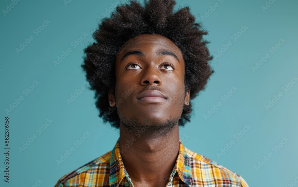 Fototapeta premium A man with a plaid shirt and dreadlocks looking up at the camera. Scene is contemplative and introspective