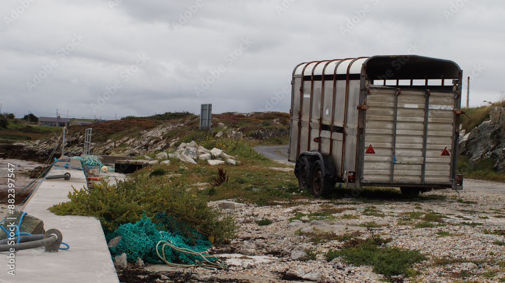 Abandoned horse box next to quay with fishing nexts and rubbish