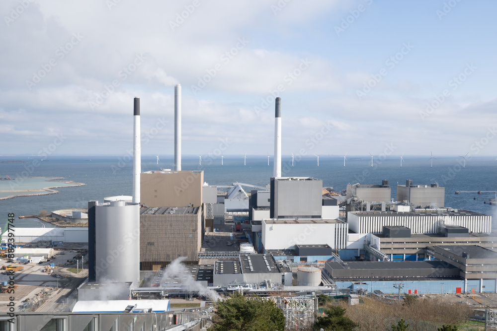 Industrial complex on the coast with wind turbines in the distance Industrial complex on the coast with wind turbines in the distance