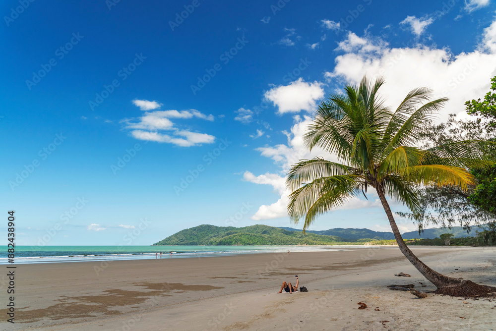 Picturesque tropical golden sandy Thornton Beach in Daintree rainforest under blue sky with white clouds, Queensland, Australia. Thornton Beach is bounded to the south by Cape Tribulation Road.