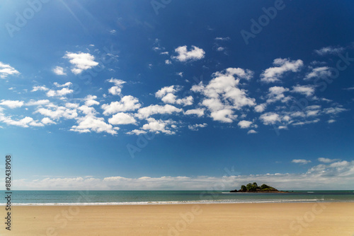 Picturesque tropical golden sandy Thornton Beach in Daintree rainforest under blue sky with white clouds, Queensland, Australia. Thornton Beach is bounded to the south by Cape Tribulation Road.