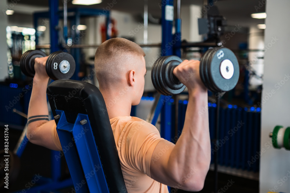 Bodybuilder lifts dumbbells during a workout in a gym Bodybuilder lifts dumbbells during a workout in a gym