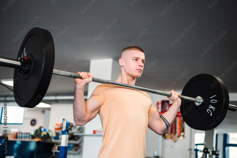 Young blond man bodybuilder trains with weights in a gym Young blond man bodybuilder trains with weights in a gym