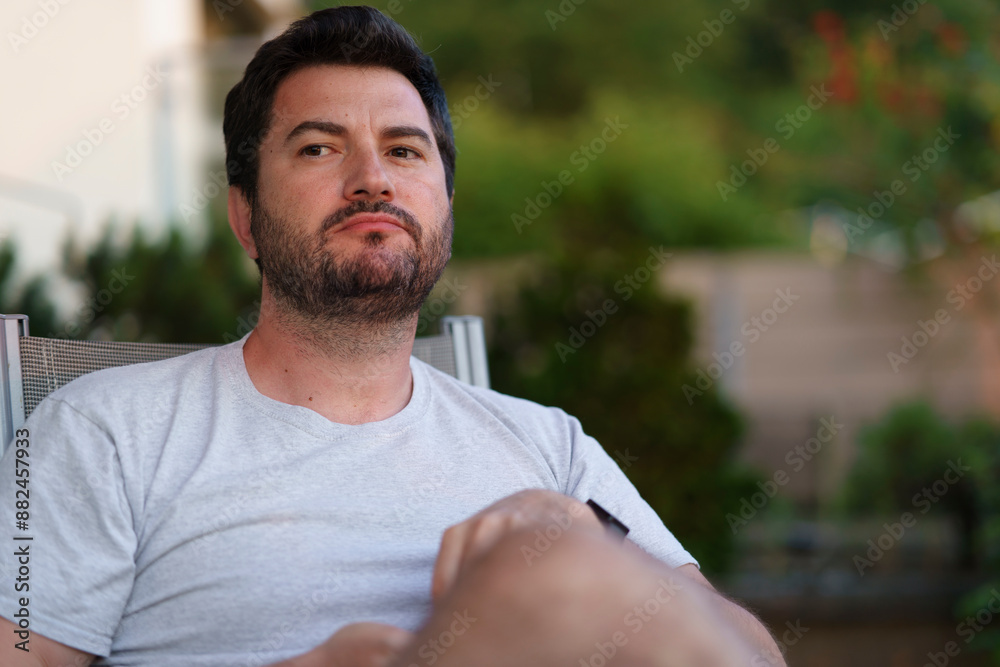 Lonely sad thoughtfully serious bearded middle-aged man sits outdoors in the rays of the sunset. Single life concept Lonely sad thoughtfully serious bearded middle-aged man sits outdoors in the rays of the sunset. Single life concept