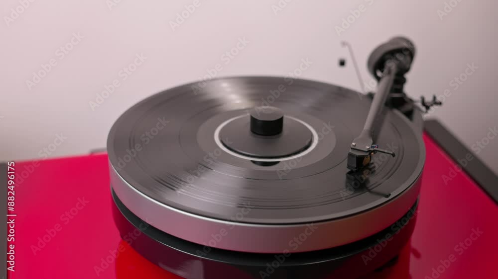 Person's hand gently lowering tonearm onto vinyl record to play music. Person's hand gently lowering tonearm onto vinyl record to play music.