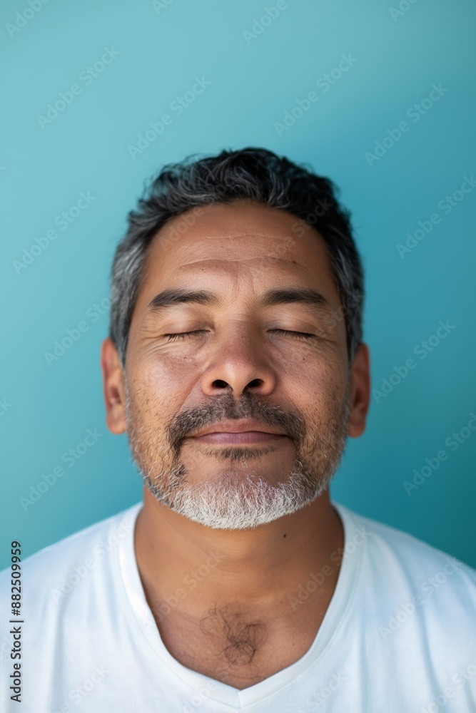 Obraz premium Man with salt and pepper hair and a beard standing with his eyes closed, embracing a moment of tranquility and serenity