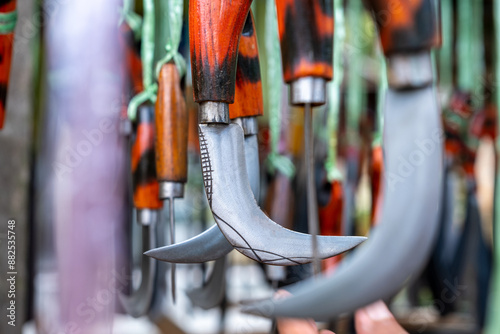 Karambit knife, a typical traditional Minangkabau silat weapon from West Sumatra hanging in a traditional weapons souvenir shop. Wallpaper background with traditional weapons theme photo