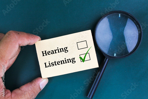 magnifying glass and paper with the words HEARING and LISTENING, select listening .concept of choose to listen than just hear, pay more attention and understand