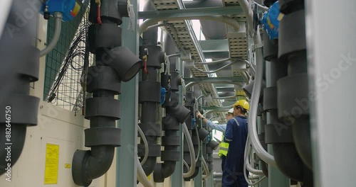 Civil engineer manager and foreman worker checking industry cooling air conditioner water cooling tower air chiller of large industrial building to control air system at construction site