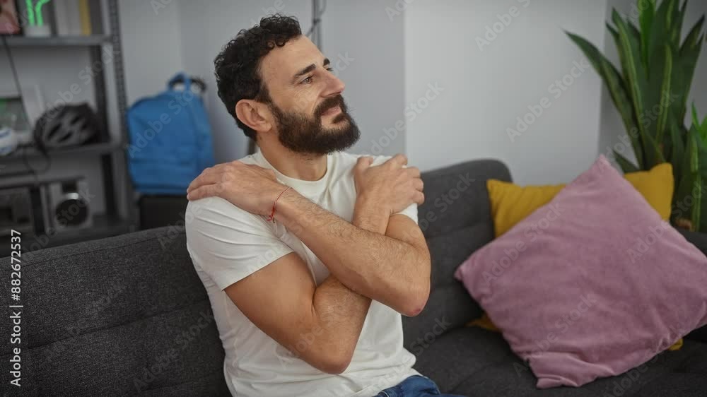 Handsome middle age man, joyously hugging himself in a white t shirt, at home. radiating positive energy, he embodies self love Handsome middle age man, joyously hugging himself in a white t shirt, at home. radiating positive energy, he embodies self love