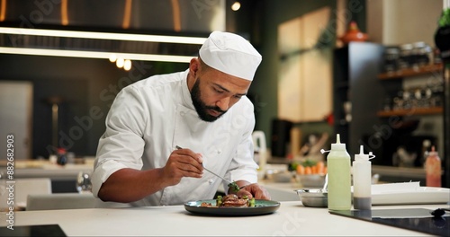 Man, chef and serious with food in kitchen at restaurant for fine dining, meal and creativity. Male employee, professional and cooker with pride for culinarily, hospitality and catering service photo