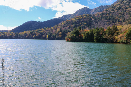 秋の日光の風景。湯の湖。黄葉する岸辺の森。