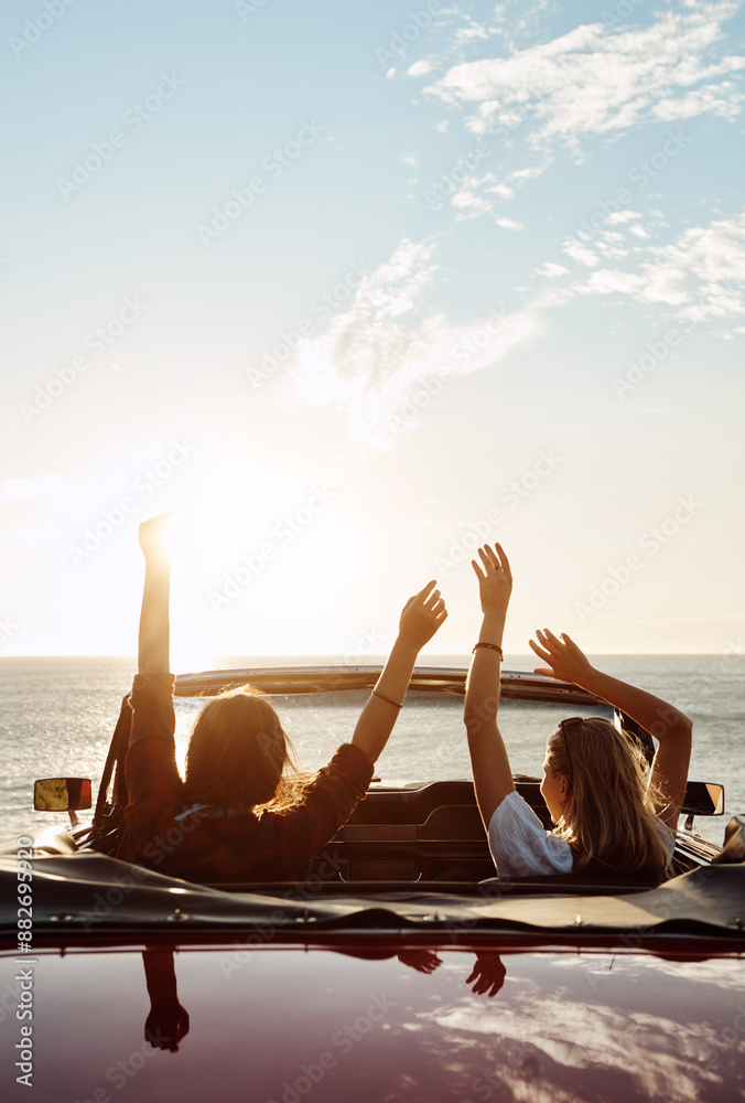 Naklejka premium Happy people, celebration and friends in convertible for adventure, freedom and holiday or road trip by beach. Back of woman with arms up for success, winning and dance in car and watching sunset