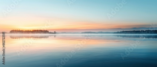 Serene lakeside sunrise with clear reflections of vibrant colors and misty horizon, capturing the tranquil beauty of nature in the early morning.