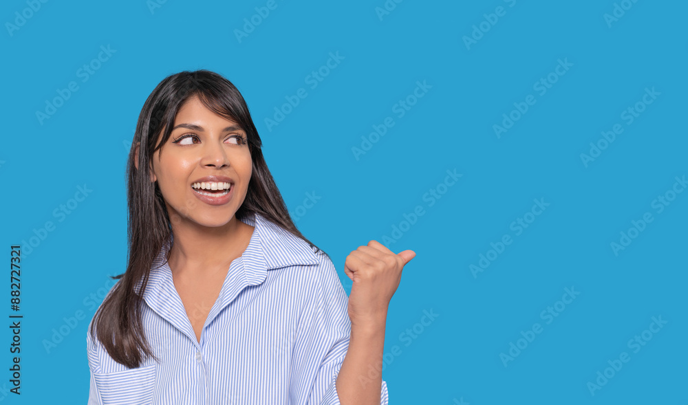 Smiling Woman Pointing Right Against Blue Background Smiling Woman Pointing Right Against Blue Background