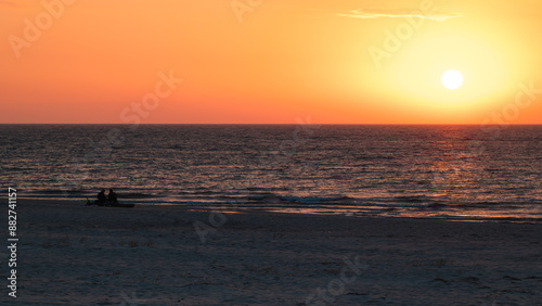 Obraz na płótnie Beautiful sunset over the Baltic Sea. Silhouettes of two people on the beach watching the sunset. Slajszewo, Poland w salonie
