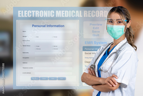 Female docor stood with her arms crossed in front of medical record screen.