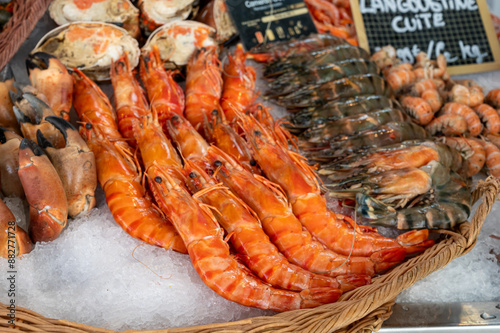 Assortment of fresh daily catch of prawns, seashells, molluscs on ice on fish market in Brittany, France, English translation: differens French names of seafood photo