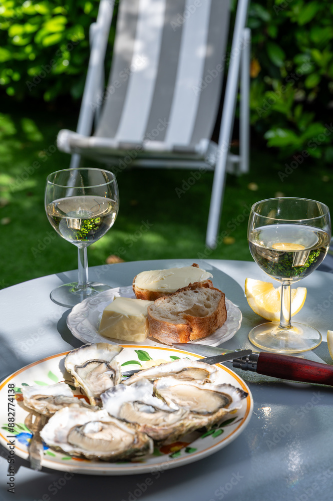 Plate with fresh live oysters with citron, bread, butter and white wine served at restaurant in oyster-farming village, Arcachon bay, Gujan-Mestras port, France Plate with fresh live oysters with citron, bread, butter and white wine served at restaurant in oyster-farming village, Arcachon bay, Gujan-Mestras port, France