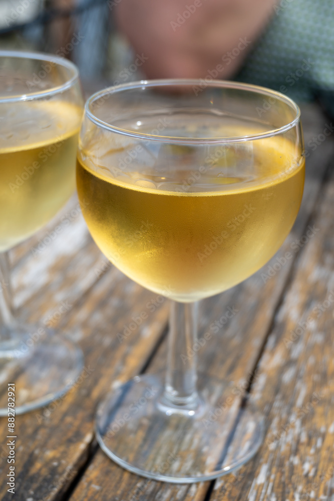 Tasting of Bordeaux white wine in Sauternes, left bank of Gironde Estuary, France. Glasses of white sweet French wine served in outdoor restaurant Tasting of Bordeaux white wine in Sauternes, left bank of Gironde Estuary, France. Glasses of white sweet French wine served in outdoor restaurant