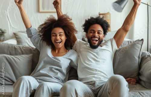 Excited Couple Celebrating a Victory on the Couch at Home