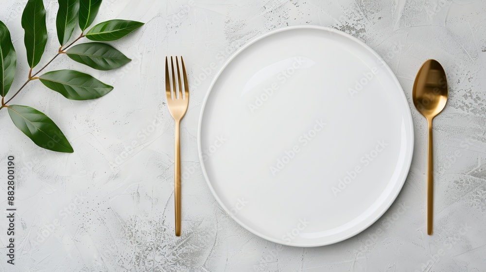 A simple table setting featuring two gold forks, a knife, and a spoon on a white napkin, with two white plates on a grey surface A simple table setting featuring two gold forks, a knife, and a spoon on a white napkin, with two white plates on a grey surface