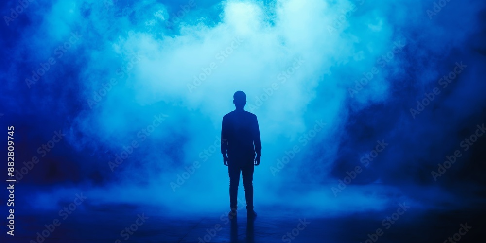 Fototapeta premium Silhouette of person in thick blue smoke creating mysterious atmosphere, mystery concept