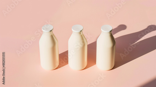 Three milk bottles rest on a soft pink surface, bathed in gentle morning light. The minimalist design emphasizes purity and freshness. Morning Light Dairy.