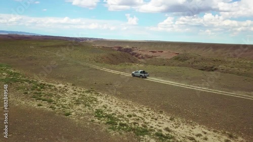 Pickup truck traveling fast on a dirt road on the edge of a beautiful canyon. Traveling through natural sights. Timerlik Canyon. Kazakhstan