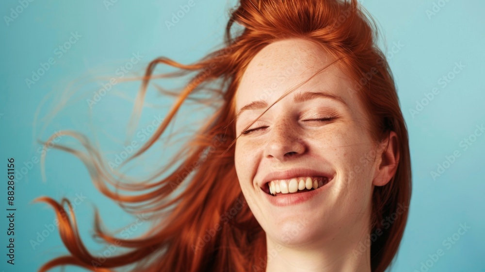 A woman with flowing red hair laughs with her eyes closed, bathed in the warm glow of the sun against a bright blue sky. A woman with flowing red hair laughs with her eyes closed, bathed in the warm glow of the sun against a bright blue sky.