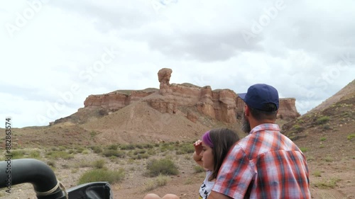 Father and daughter traveling in nature. Bearded man and girl sit in the trunk of a pickup truck and admire the surrounding landscape of an unusual canyon. Traveling through natural attractions photo