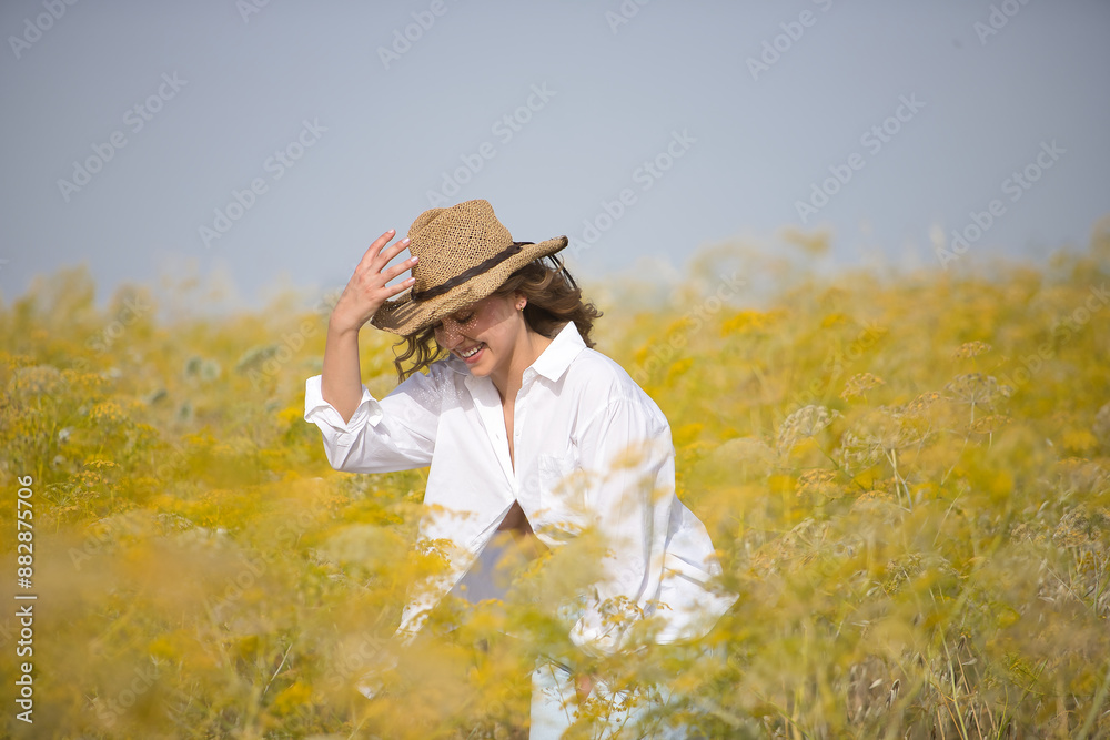 Young woman, farmer, beautiful, blonde, eyes closed, wearing a white shirt, jeans and hat, posing very happily and smiling in the middle of a fennel field. Concept beauty, happiness, nature. Young woman, farmer, beautiful, blonde, eyes closed, wearing a white shirt, jeans and hat, posing very happily and smiling in the middle of a fennel field. Concept beauty, happiness, nature.