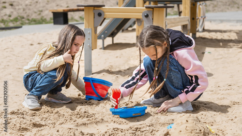 Adorable 4 years old little girl is playing the sand with her friend sisters with fully happiness moment, concept of outdoor freeplay for kid development and social skill for childhood. photo