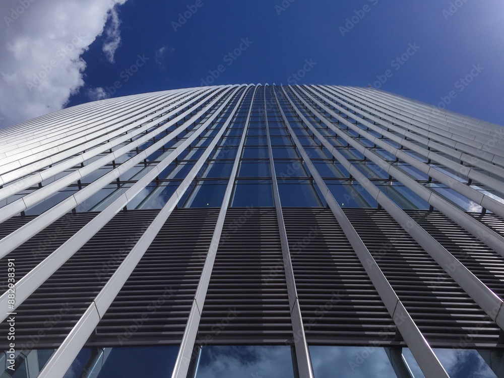 Low angle shot of the modern architecture of a high-rise building against a blue sky on a sunny day