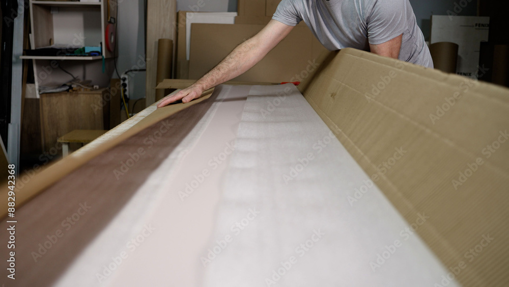 Close-up of a hand packing a cardboard box with tape in a warehouse. Packaging goods in a cardboard box, close-up. Close-up of a hand packing a cardboard box with tape in a warehouse. Packaging goods in a cardboard box, close-up.