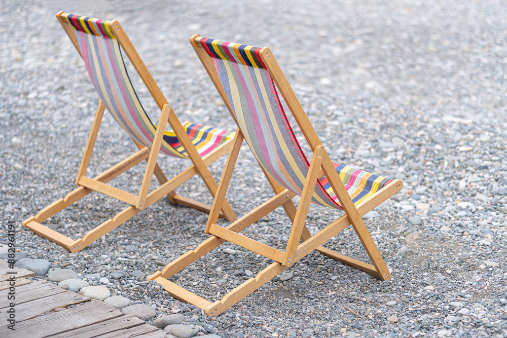 Two beach folding chairs on a pebble beach. Two beach folding chairs on a pebble beach.