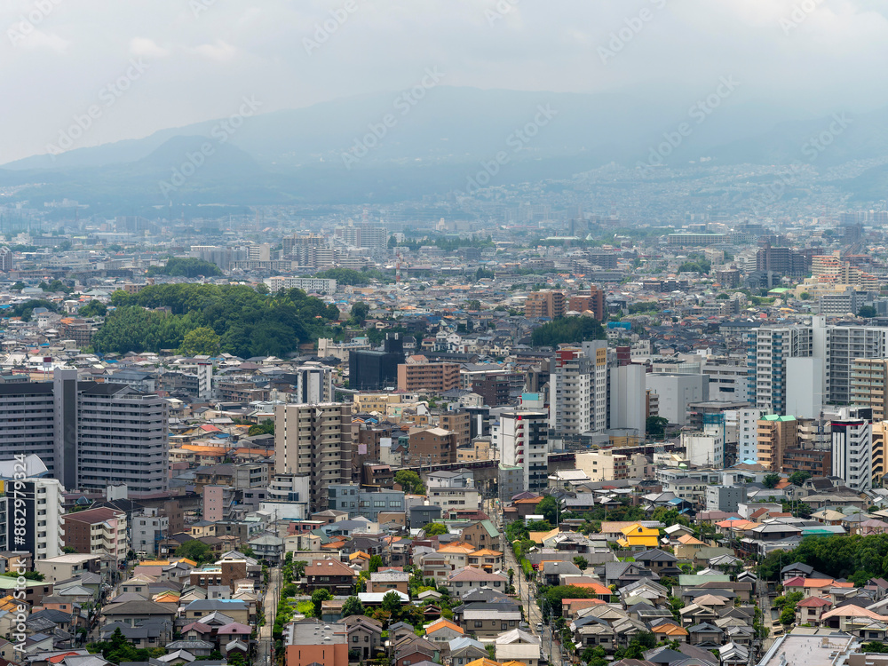 Obraz premium 展望台から見る都市と雨に霞む山の風景