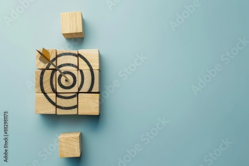 Wooden blocks with a target and arrow on a light blue background, symbolizing goal achievement and strategic planning in business. Flat lay, high quality, minimalist design photo