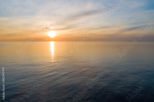 Serene sunset over calm ocean waters with a distant horizon.