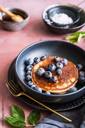 Pancake mit Heidelbeeren und Honig auf einem schwarzen Teller. Frühstück, servierfertig. photo