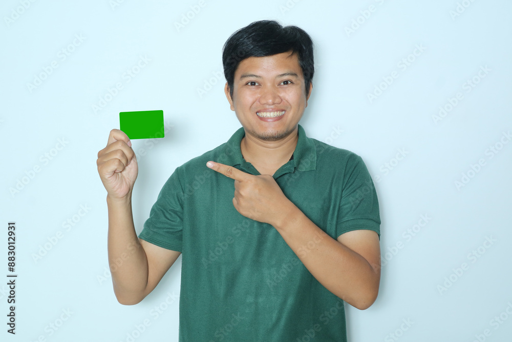 Young Asian man smiling confident while right hand pointing to green card that he hold. Wearing a green t-shirt Young Asian man smiling confident while right hand pointing to green card that he hold. Wearing a green t-shirt