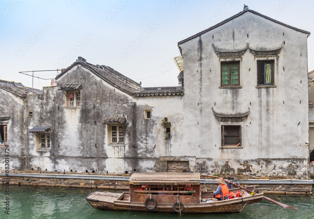 Traditional wooden boat on the canal with old houses in Suzhou, China