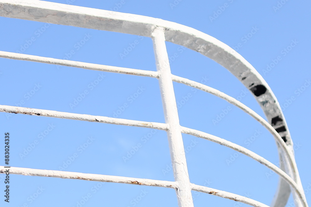 Close-up shot of a metal railing against a bright blue sky. Close-up shot of a metal railing against a bright blue sky.