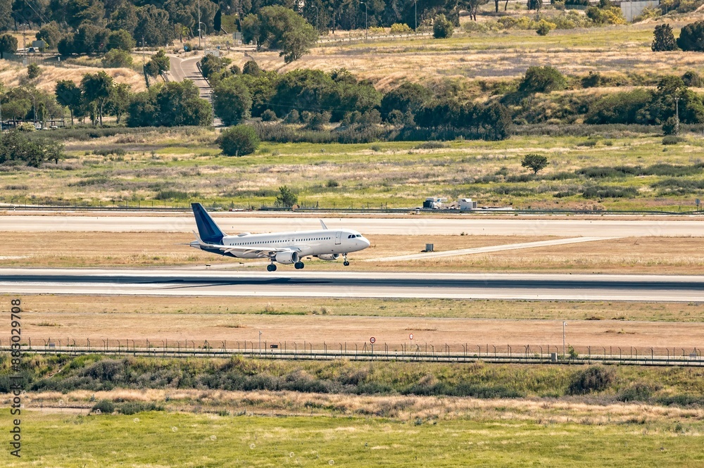 Commercial airplane with a white fuselage and dark blue tail landing on the runway. Commercial airplane with a white fuselage and dark blue tail landing on the runway.