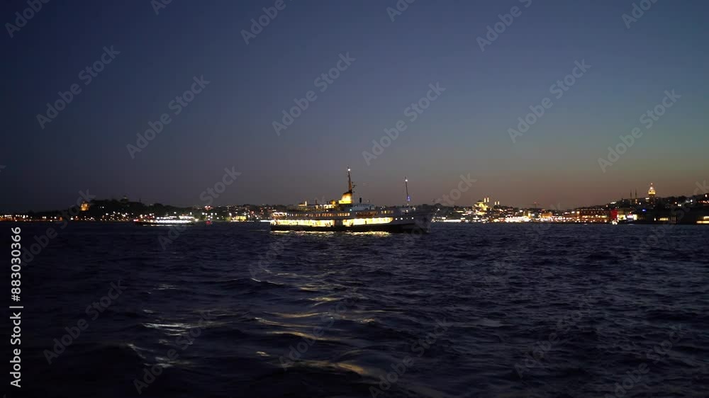 A ferry boat sailing on the Bosphorus at night with city lights in the background A ferry boat sailing on the Bosphorus at night with city lights in the background